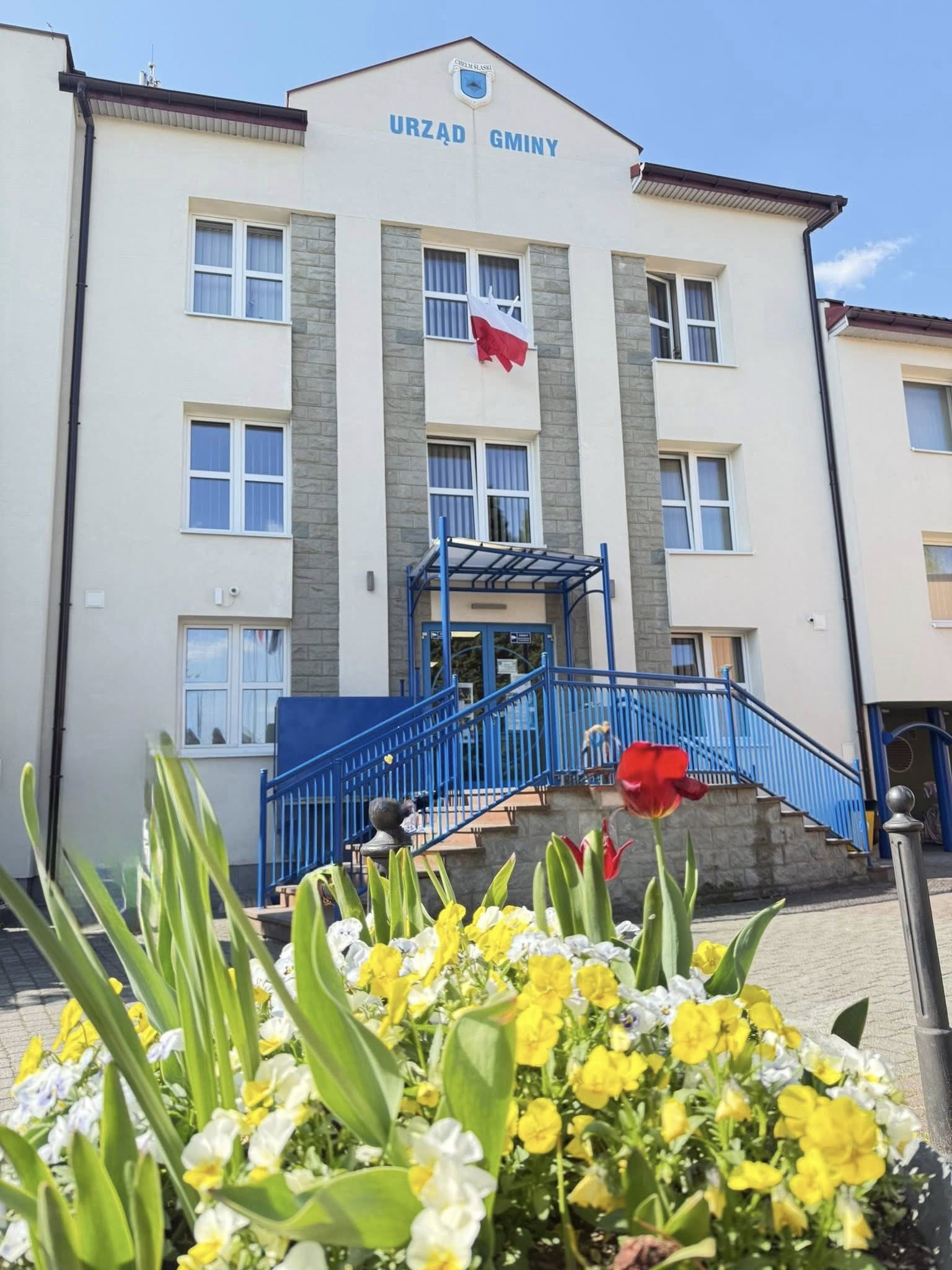 Budynek Urzędu Gminy CHełm Śląski. Na zdjęciu obiekt i kwiaty