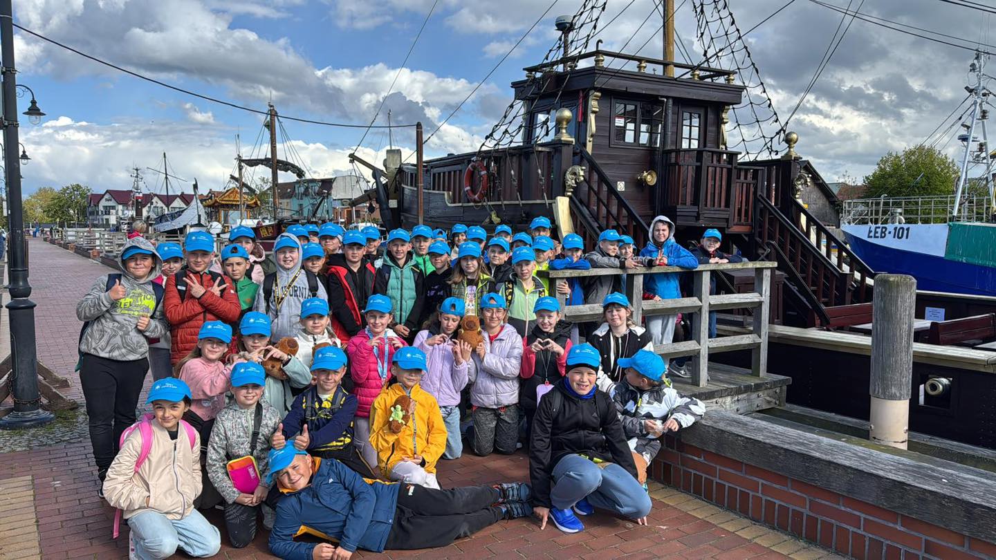 Dzieci na molo pozujące do zdjęcia przy łodzi rybackiej 