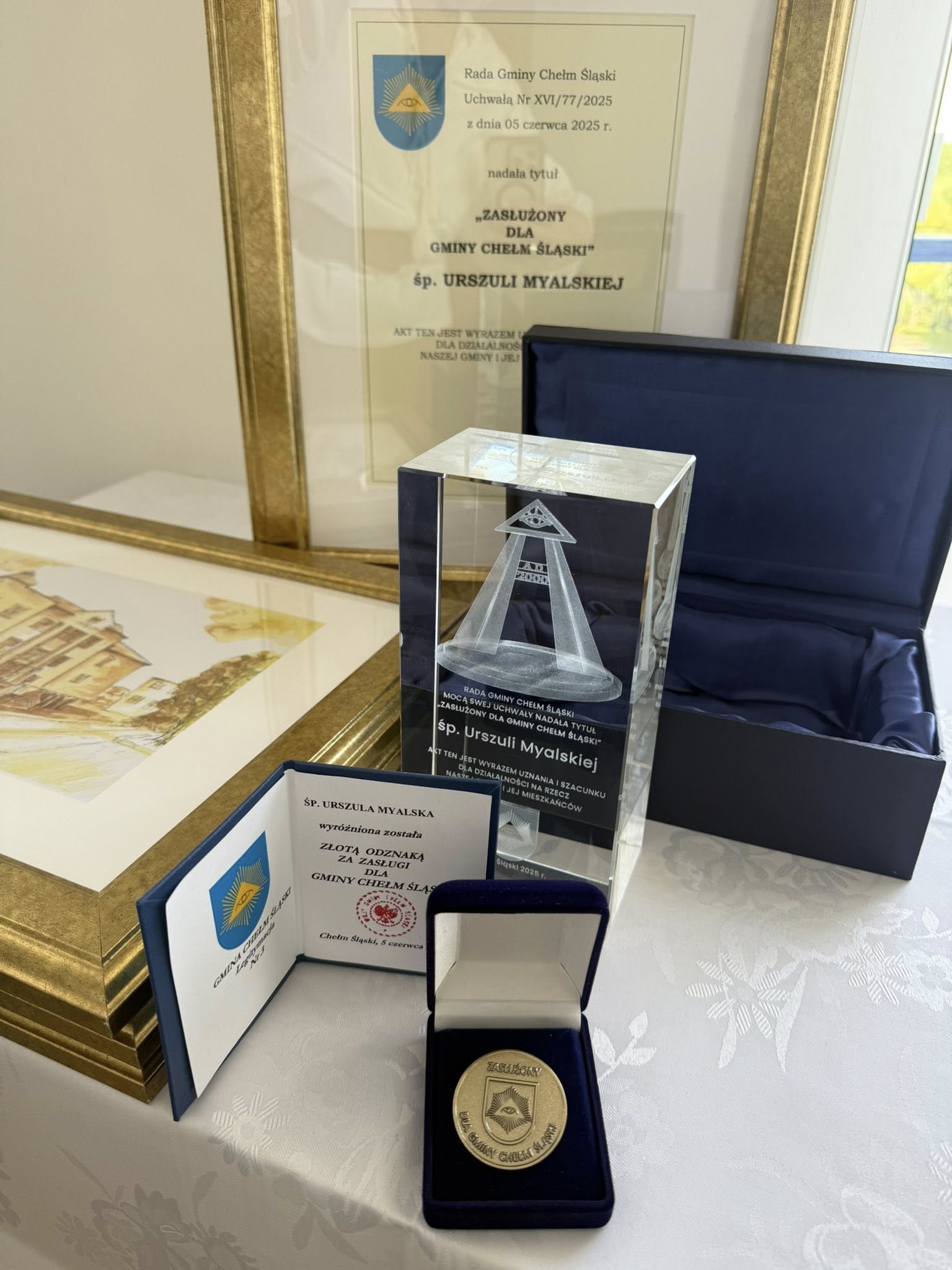 Na obrazku dyplom, medal, legitymacja i statuetka