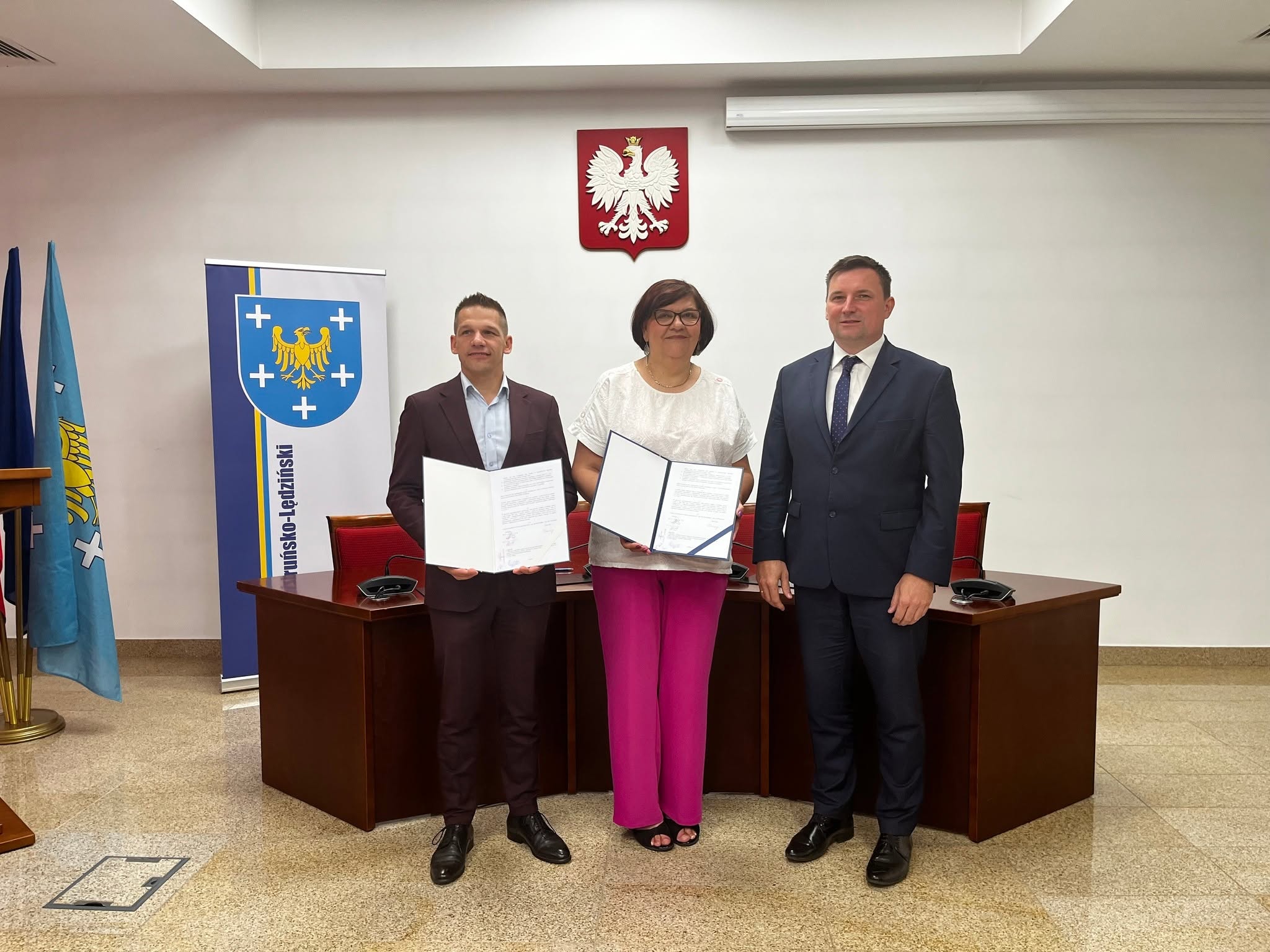 Trzy osoby pozujące do zdjęcia w pomieszczeniu