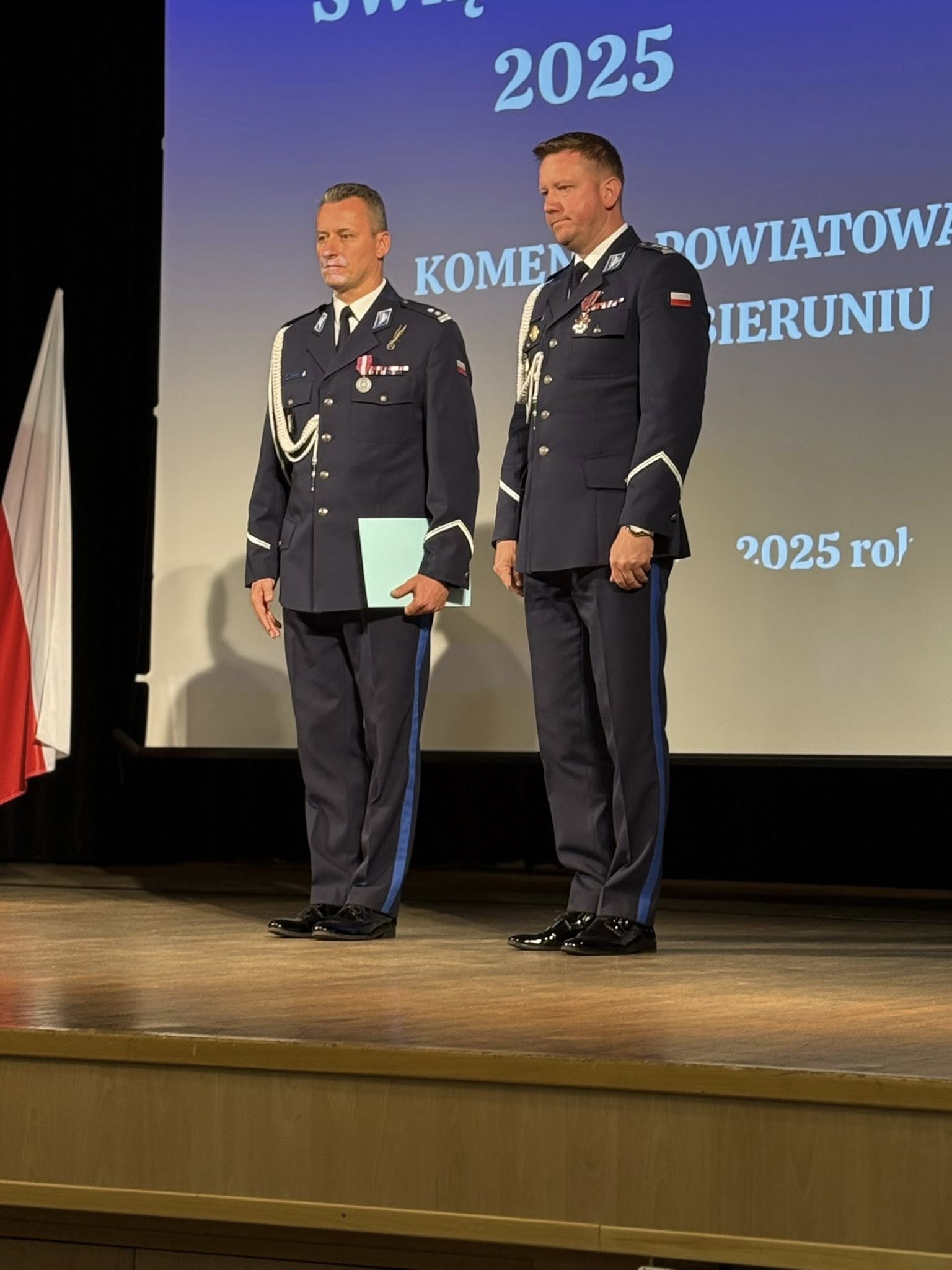 Dwaj mężczyźni w mundurach policyjnych stojący na scenie