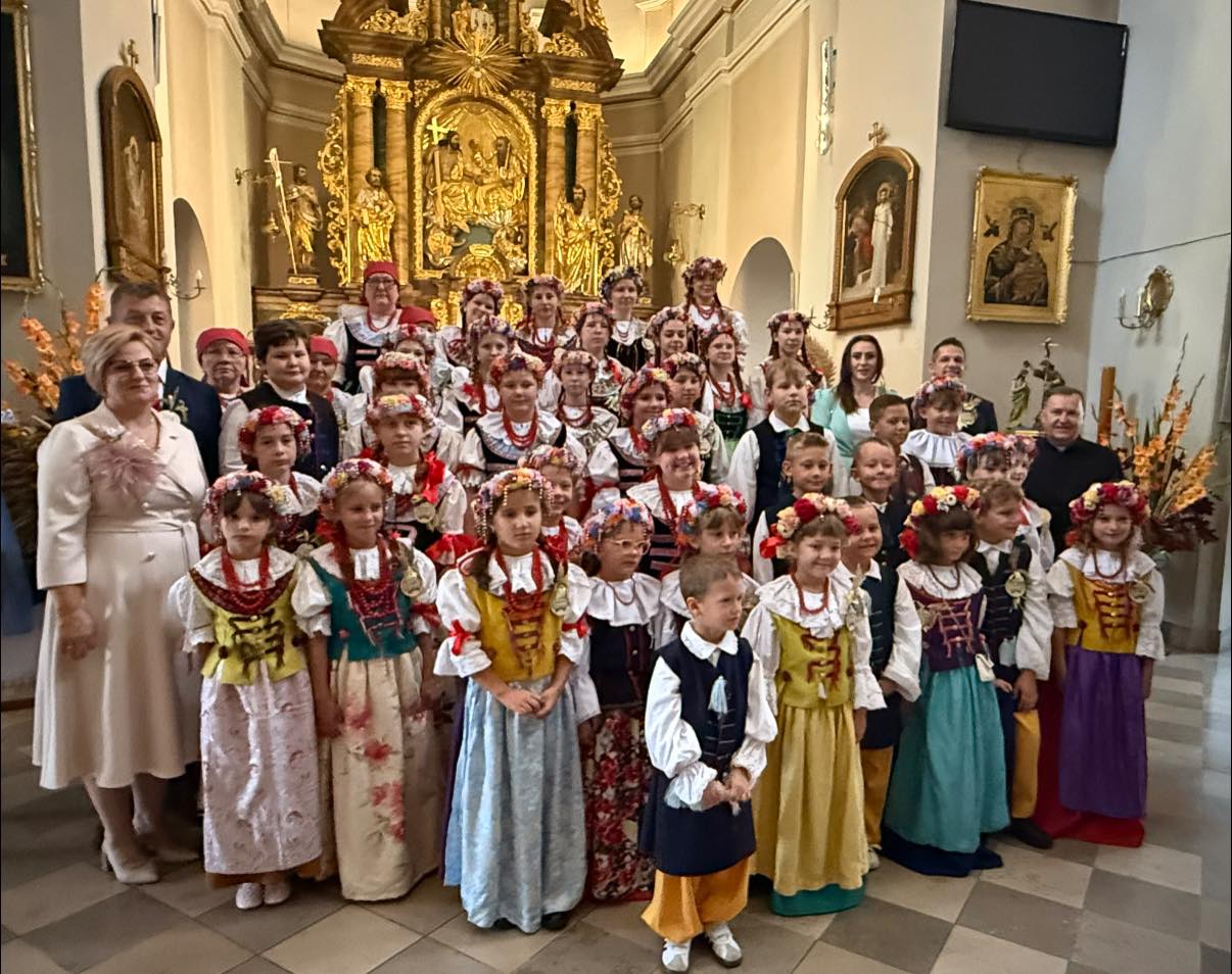 Osoby, dzieci w strojach ludowych pozujące do zdjęcia w kościele 