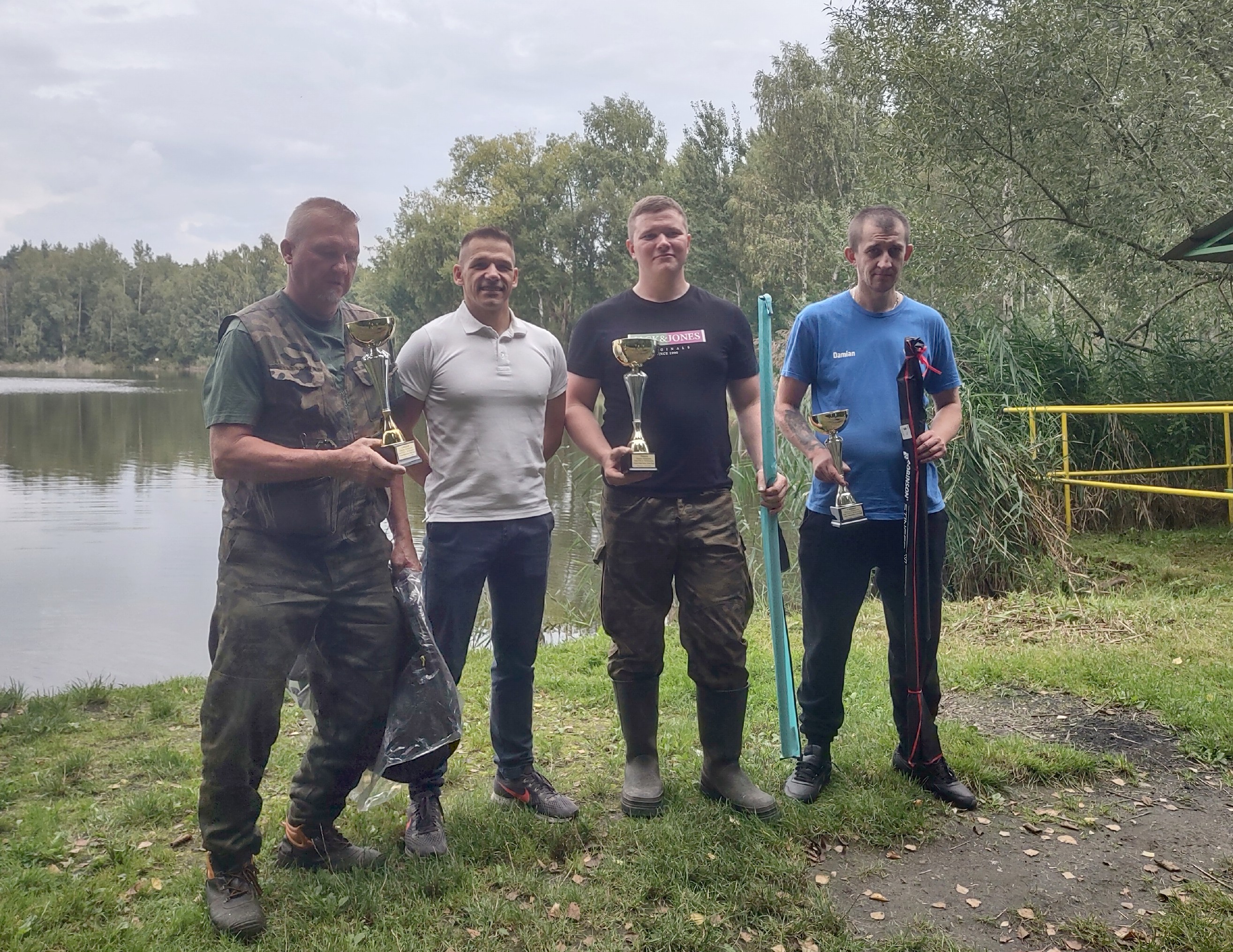 Czterej mężczyźni pozujący do zdjęcia w otoczeniu stawu