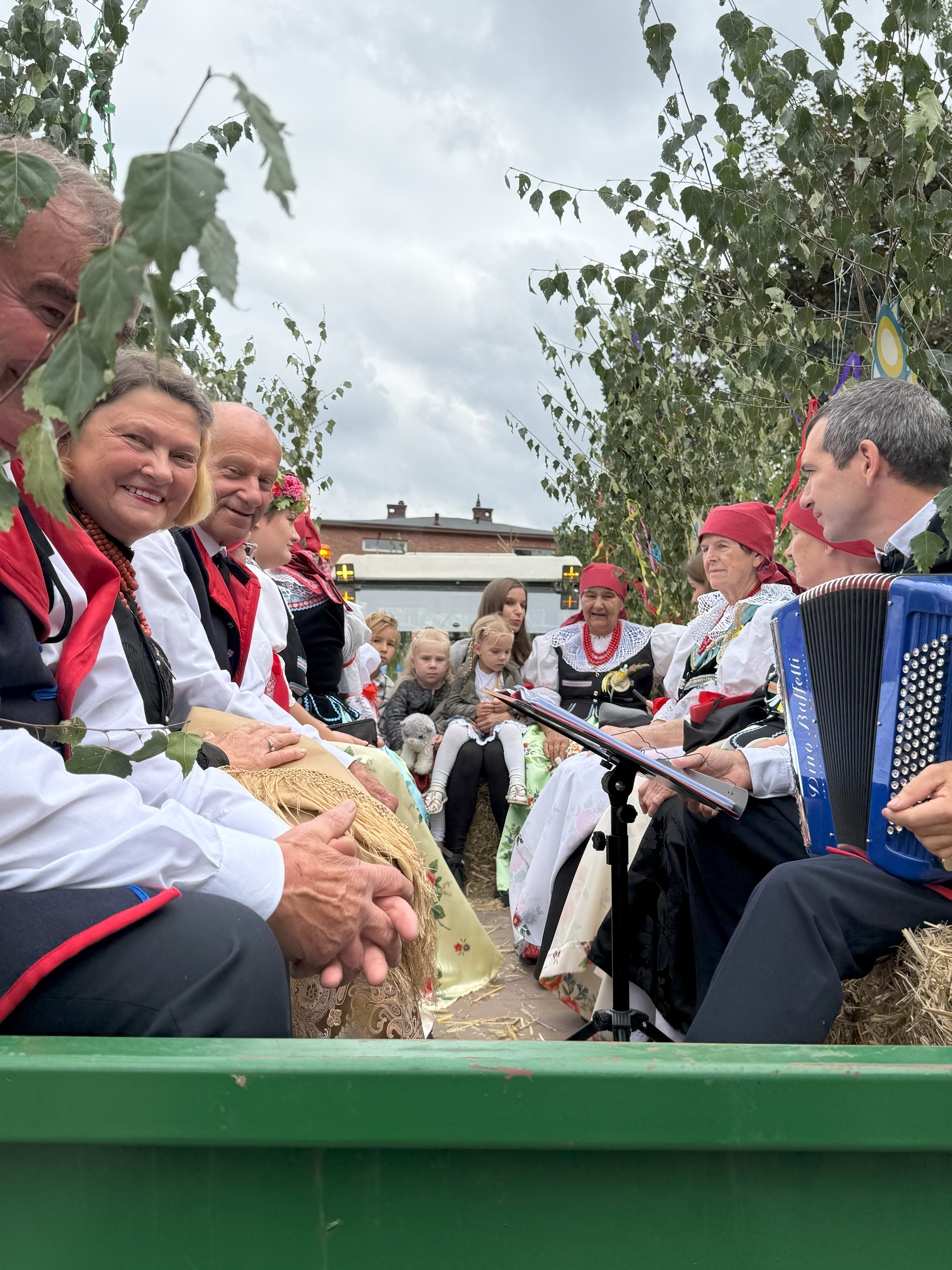 Osoby w strojach ludowych siedzące na wozie 