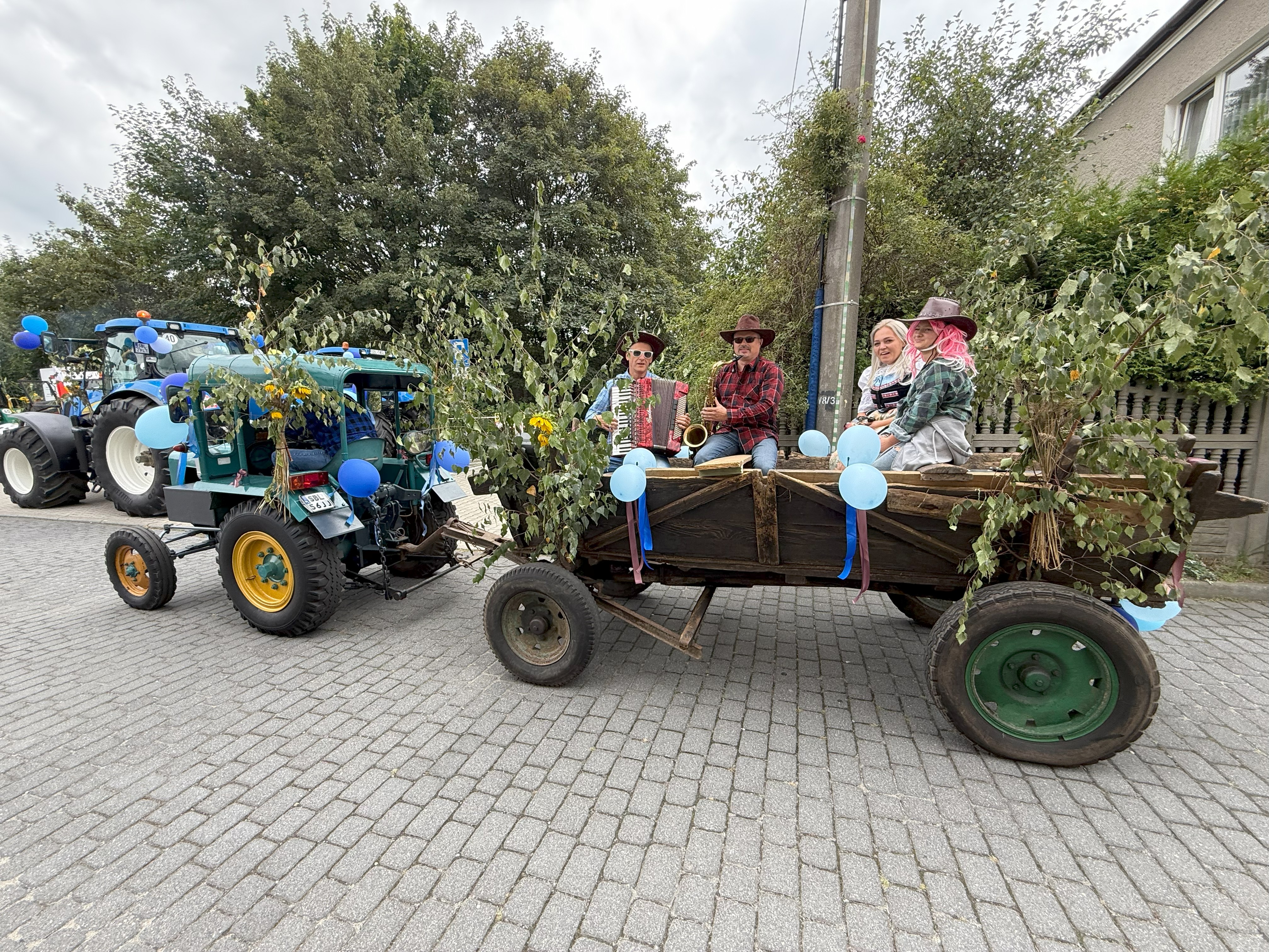 Stary traktor z wozem, na którym siedzą osoby 