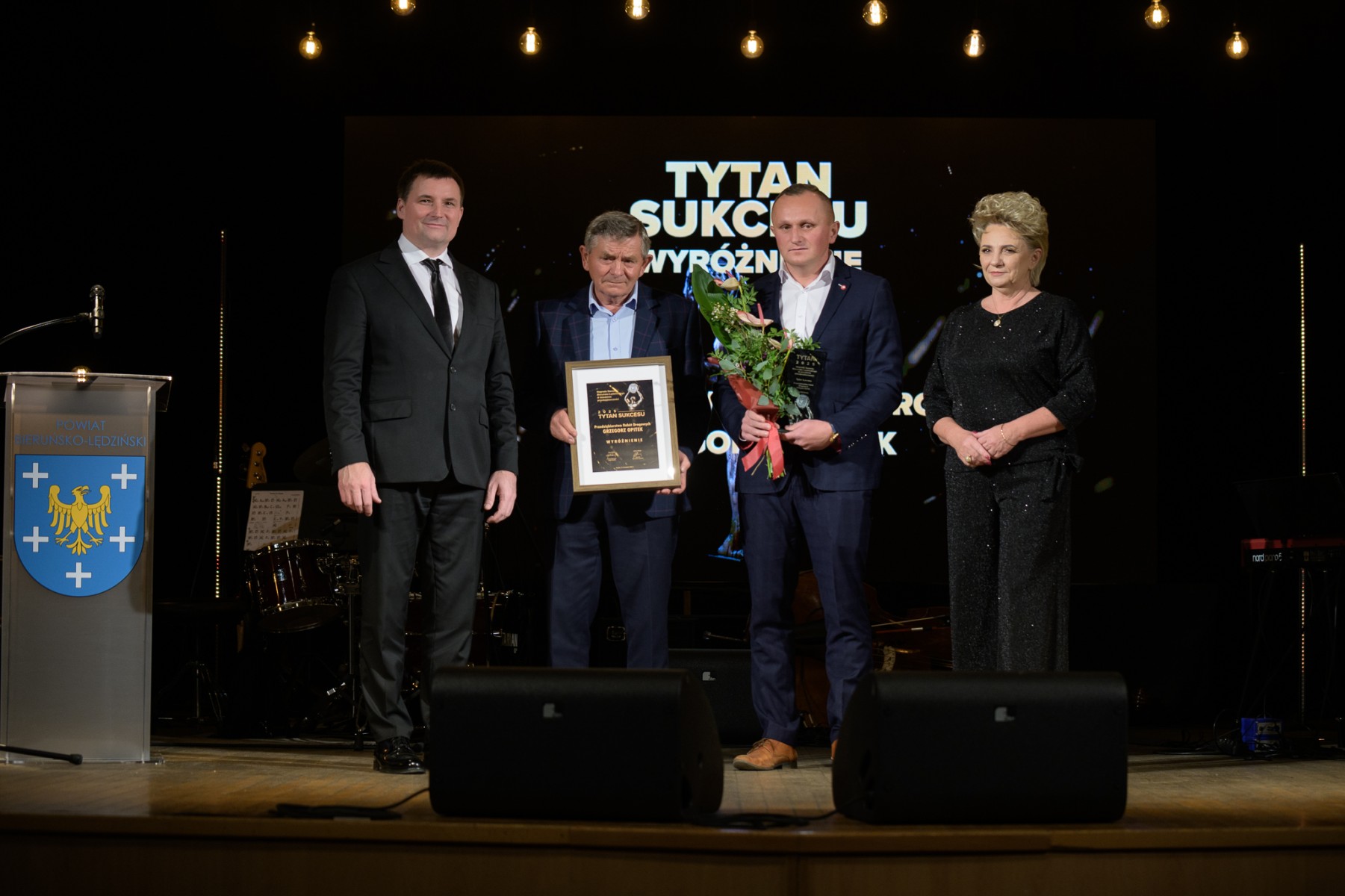 Trzech mężczyzn i kobieta pozujacy do zdjęcia w pomieszczeniu 