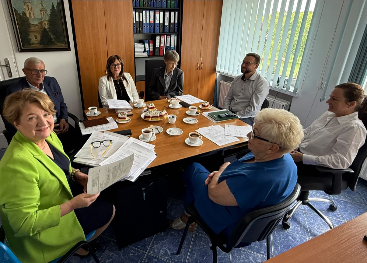 Osoby siedzące w pomieszczeniu przy stole 