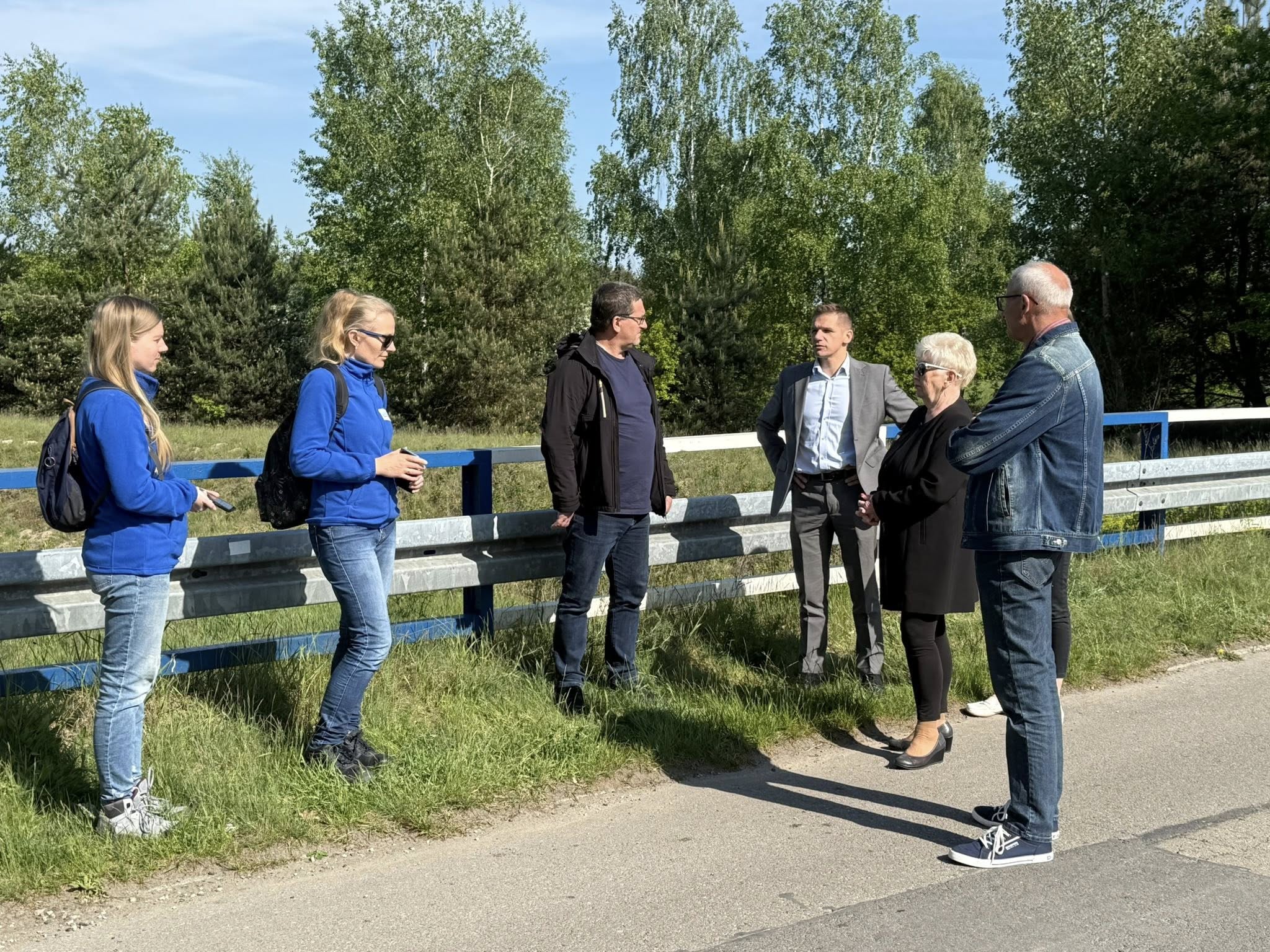 Osoby stojące przy cieku wodnym na moście